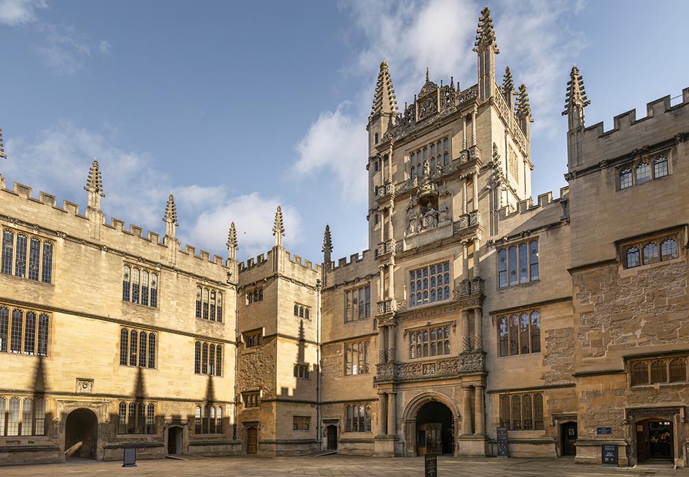 A large stone courtyard surrounded by tall stone buildings with a tower