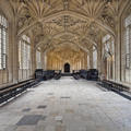 View of the Divinity School in the Bodleian Library, a 15th-century room with ornate stone ceiling carvings, a stone floor, and windows down either side of the room