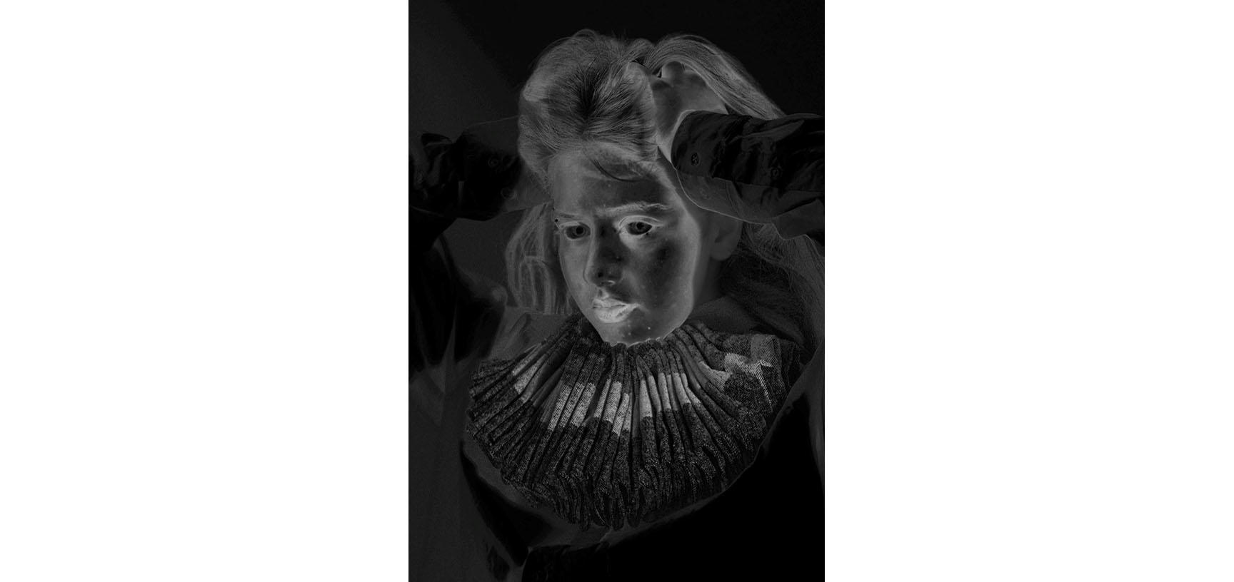 A negative image of a woman's face - she puts her hands through her hair and looks to the side of the camera