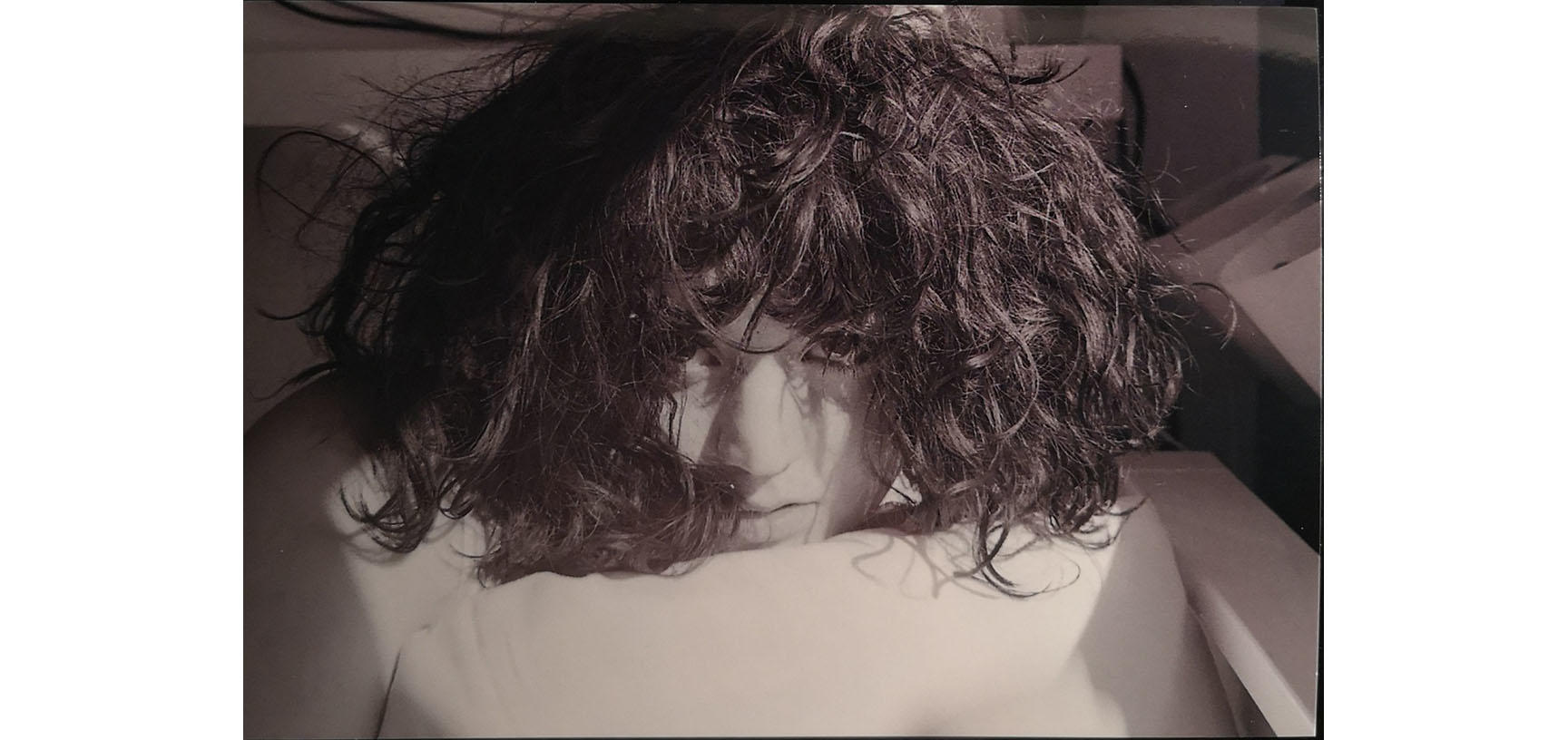 A close up on a woman's face - she looks directly at the camera and her hair tumbles down over her face