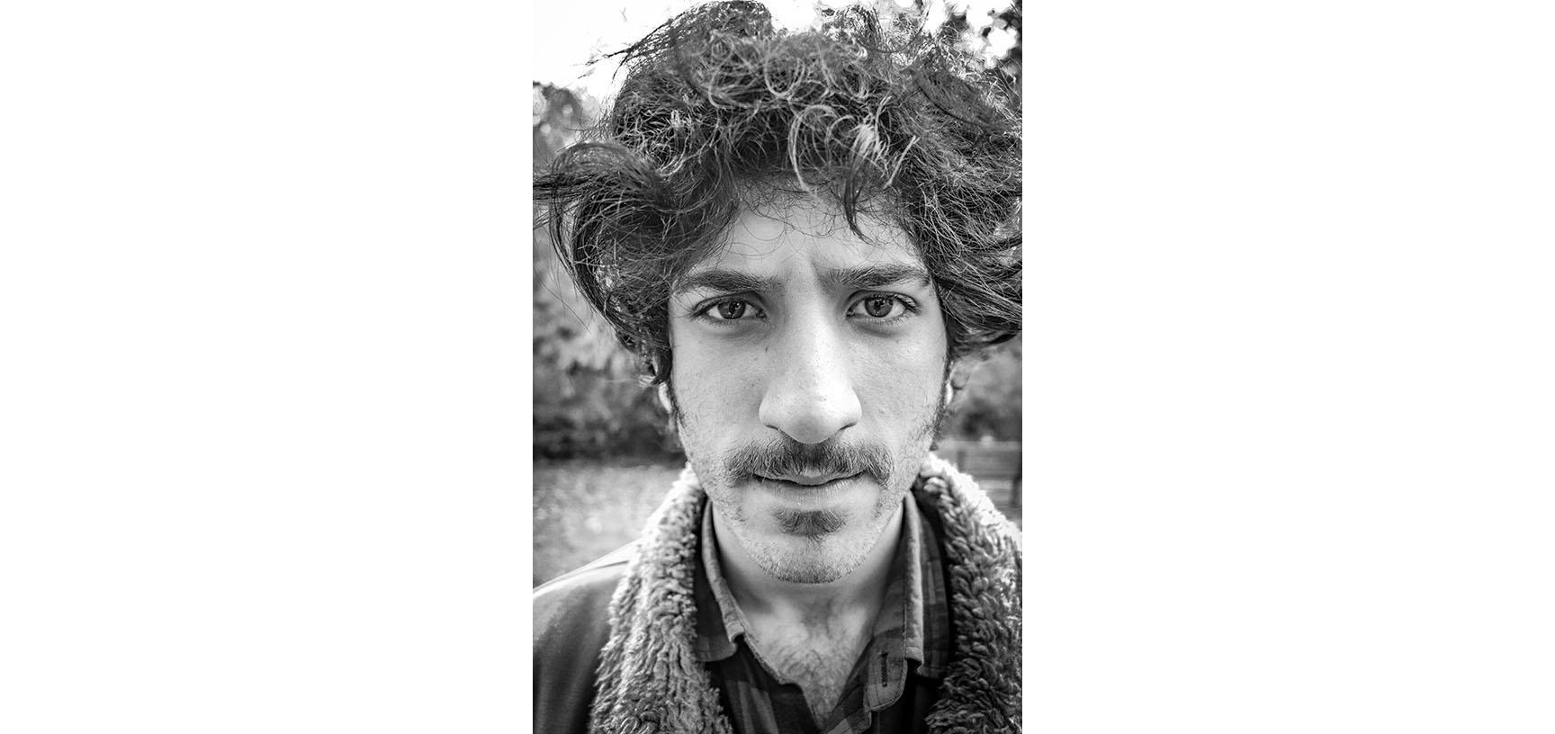 Black and white photograph of a man's head and shoulders. He is staring directly into the camera lens.